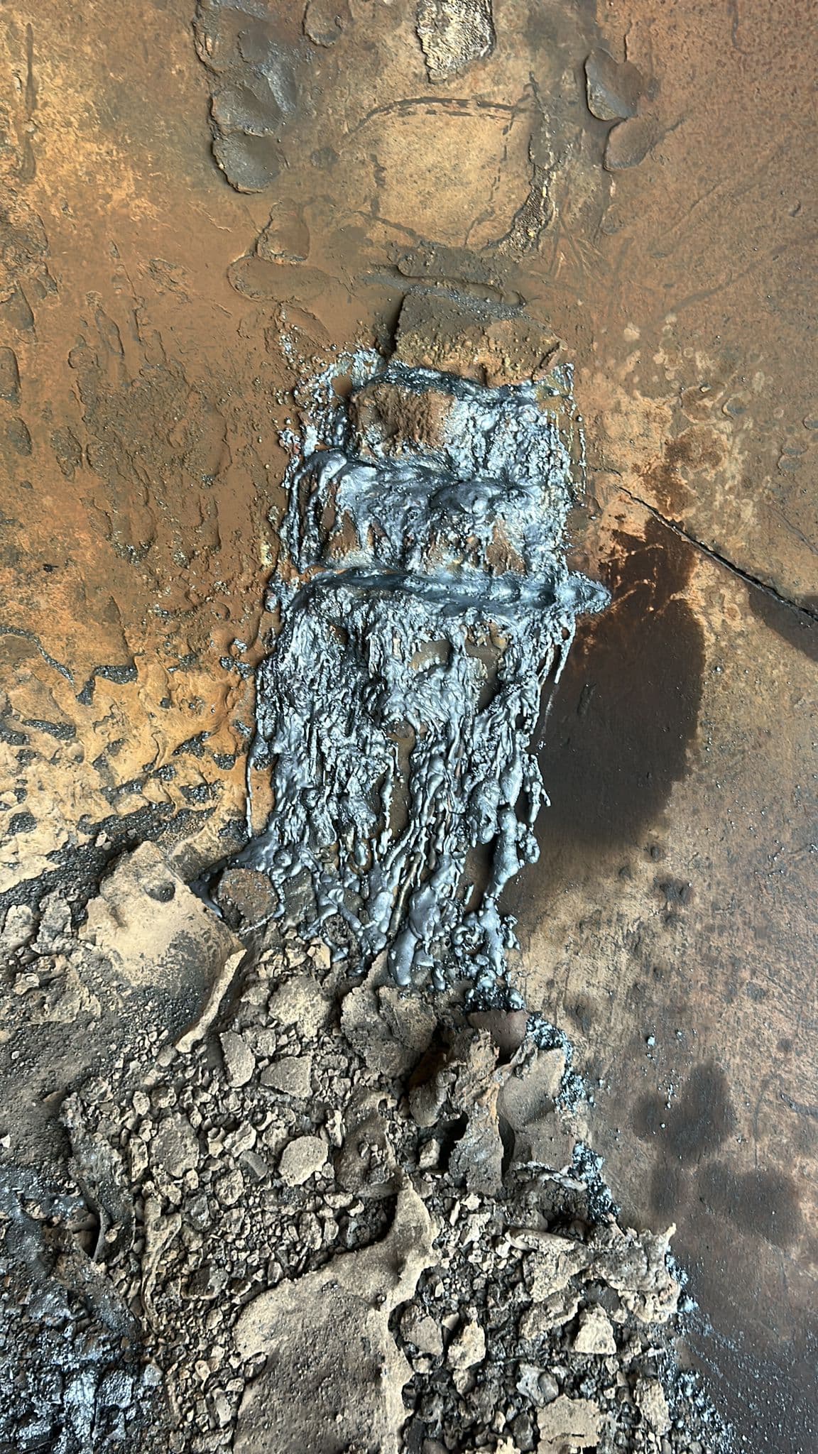Solidified metal residue and slag buildup inside industrial vessel
